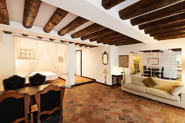 Living interior with warm ivory walls, a smooth eggshell finish, and rustic exposed wood ceiling beams by an interior painter in Ashland, MA.