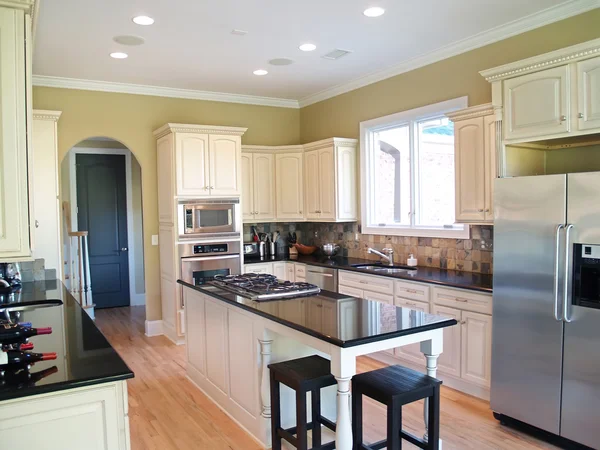 Warm yellow-green kitchen walls with detailed trim and contrasting finishes by a painting company in Dover, MA.